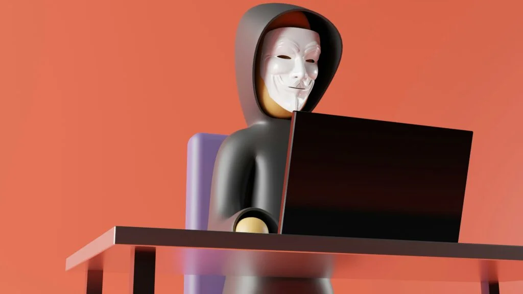 Foto einer Hacker-Puppe an einem Laptop.